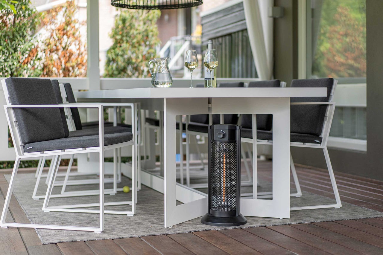 Terrassenszene mit weißem Gartentisch, Stühlen und schwarzem Heizstrahler für eine gemütliche Atmosphäre im Freien