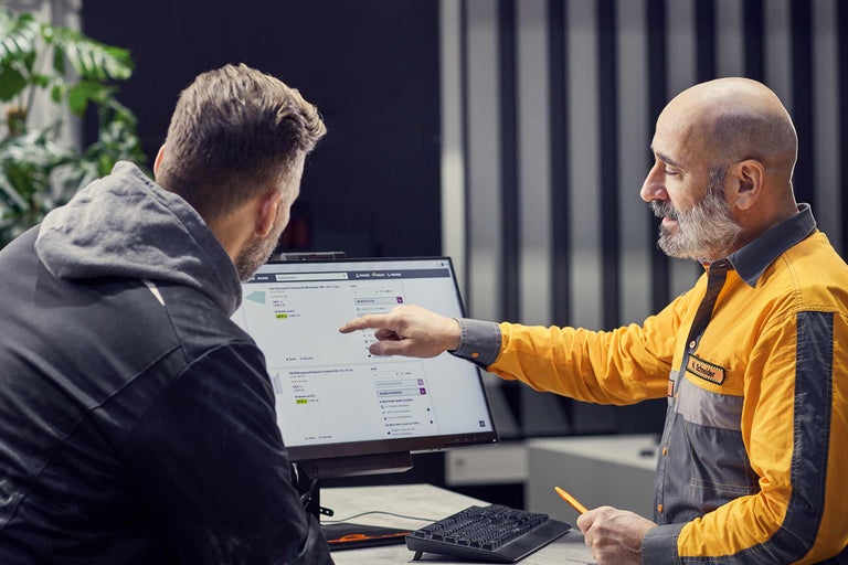 Ein Hornbach Mitarbeiter erklärt einem Kunden ein Produkt auf einem Computerbildschirm.