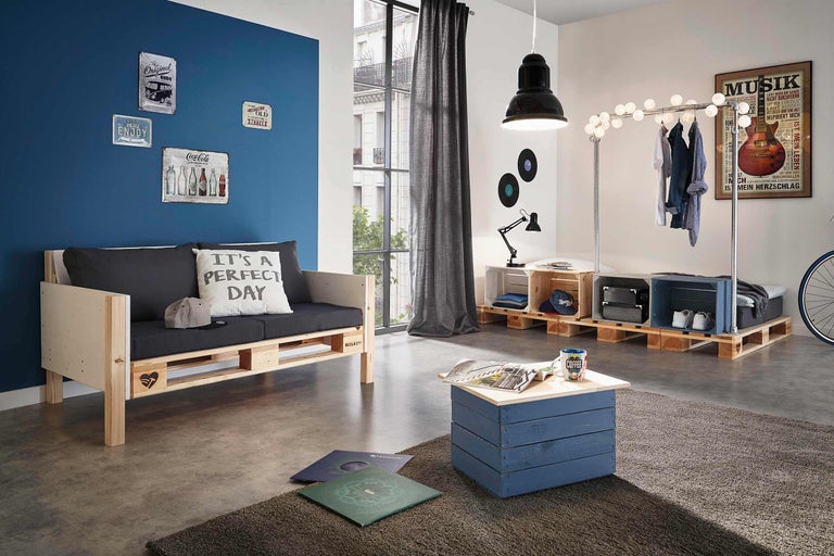 Wohnzimmer mit Palettenmöbeln, darunter Sofa, Couchtisch und Regal