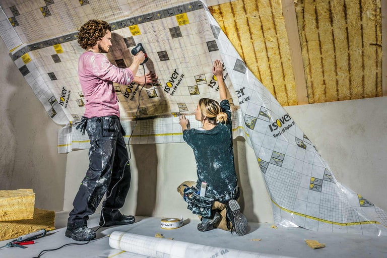 Zwei Personen befestigen eine Dampfbremsfolie von Isover an einer Dachschräge.