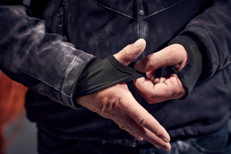 Nahaufnahme einer Person, die eine Jacke mit integrierten Ärmelstulpen anprobiert.