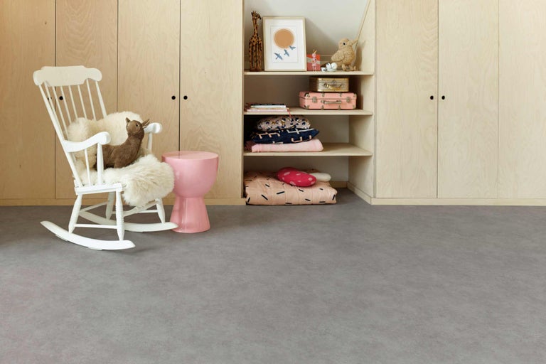 Kinderzimmer mit Holzschrank, Regalen, weißem Schaukelstuhl und grauem Boden