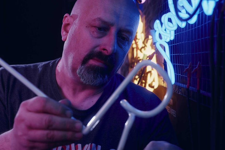 Ein Mann fertigt eine Leuchtreklame.