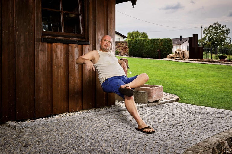 Mann sitzt an Holzwand mit Granitpflaster im Garten