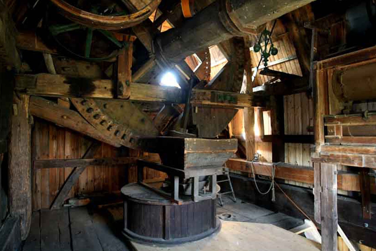 Innenraum einer historischen Mühle mit hölzernen Maschinen und Getrieben