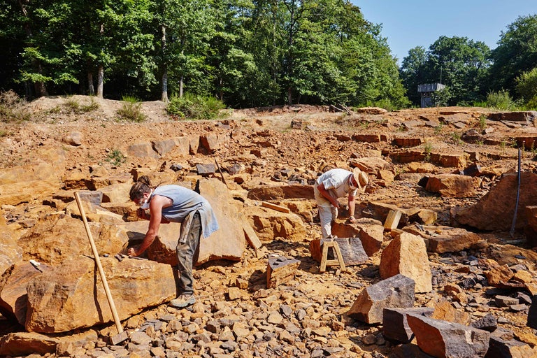Steinbrucharbeiter bearbeiten Steine im Freien.