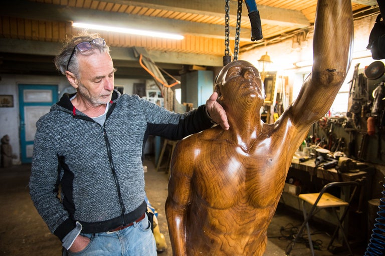 Mann betrachtet Holzskulptur eines Mannes in Werkstatt