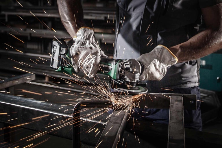 Eine Person benutzt einen Winkelschleifer zum Schneiden von Metall, wobei Funken entstehen.