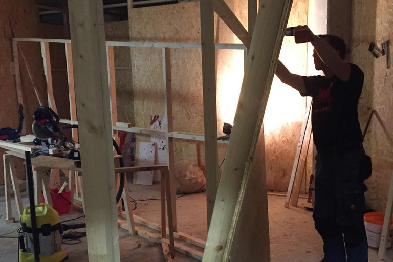 Mann bei Holzkonstruktionsarbeiten im Innenraum.