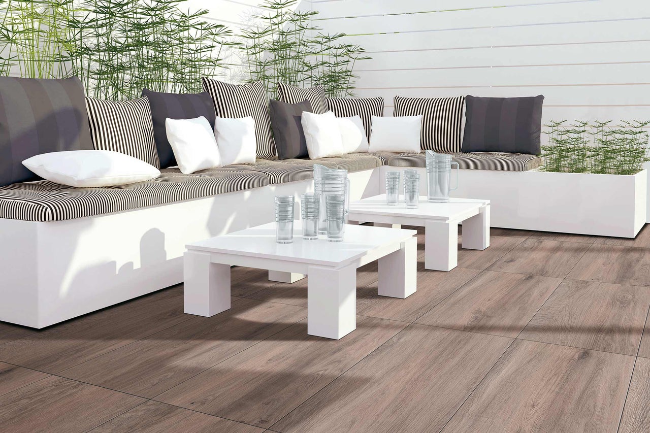 Terrasse mit Sitzgruppe, Kissen, Tischen, Gläsern und Holzboden