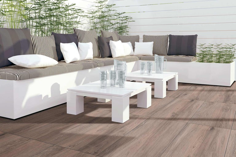 Terrasse mit Sitzgruppe, Kissen, Tischen, Gläsern und Holzboden
