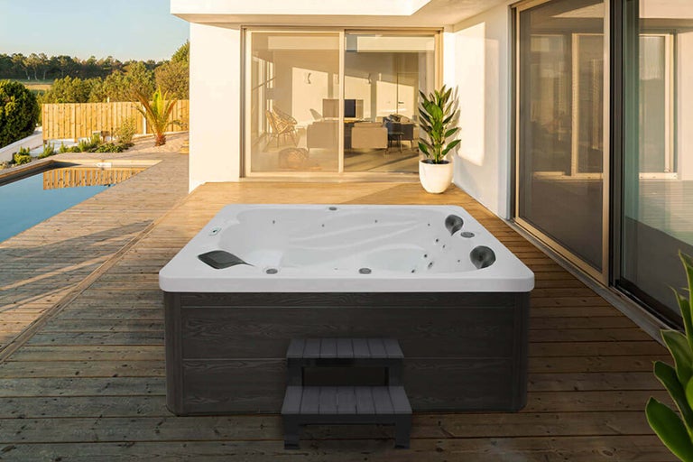 Whirlpool mit Treppe auf einer Holzterrasse neben einem Pool