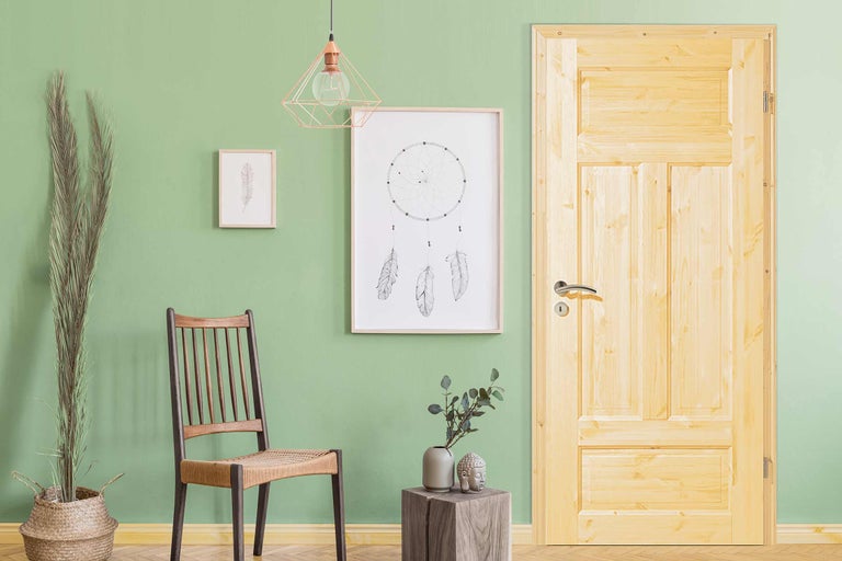 Szene mit Holztür, Stuhl, Dekoration und Wandbildern in einem hellen Raum.