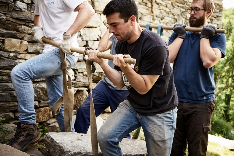 Gruppe von Personen trägt Lasten mit Tragegestell