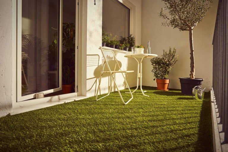 Balkon mit Kunstrasen, Stuhl, Tisch und Pflanzen