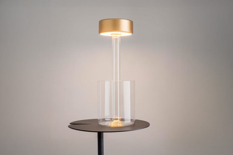 Tischleuchte mit Zylinder aus Klarglas auf einem Beistelltisch