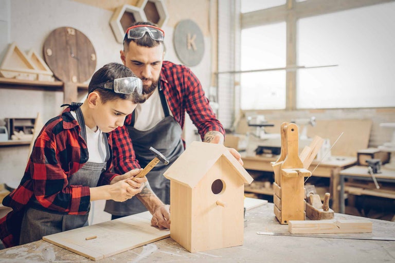 Vater und Sohn bauen gemeinsam ein Vogelhaus in der Werkstatt.
