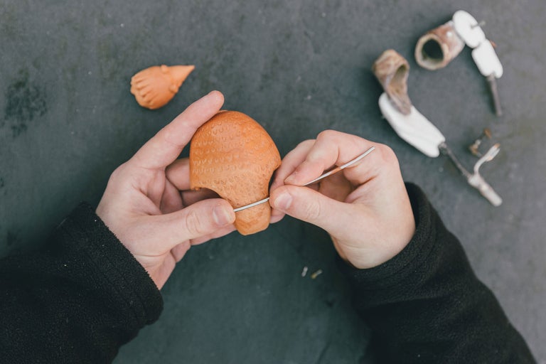 Detailaufnahme von Händen, die eine Pfeife aus Ton formen, Handwerk