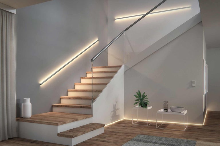 Treppenhaus mit Holzstufen, Glasgeländer und linearen Wandleuchten