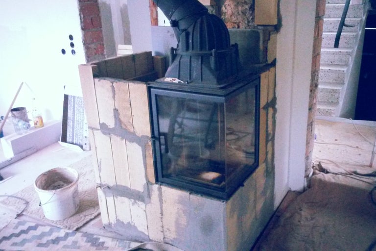 Unfertiger Kamin mit Glasfront und Schornsteinanschluss.