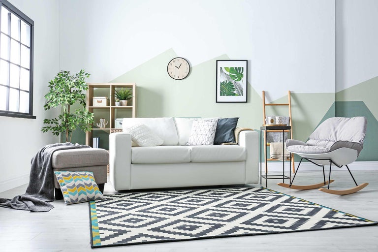 Wohnzimmer mit Sofa, Sessel, Teppich und Dekoration