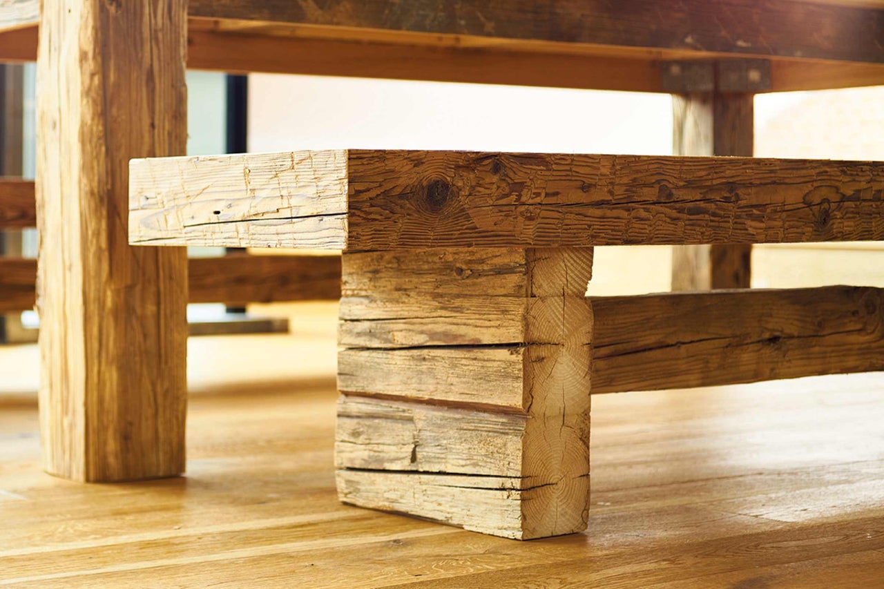 Detailansicht eines Holztisches mit rustikalen Holzbeinen und einer massiven Tischplatte