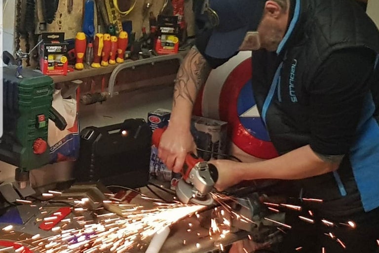 Ein Mann benutzt einen Winkelschleifer in einer Werkstatt, wobei Funken sprühen