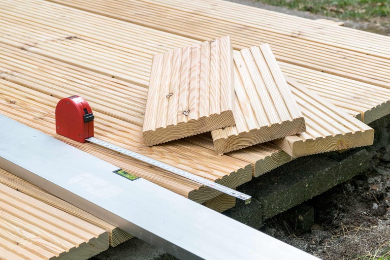 Aufbau einer Holzterrasse mit Terrassendielen, Wasserwaage und Rollbandmass
