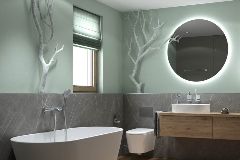 Modernes Badezimmer mit freistehender Badewanne, wandhängender Toilette und Holz-Waschtisch. Ein großer runder beleuchteter Spiegel und dekorative Äste.