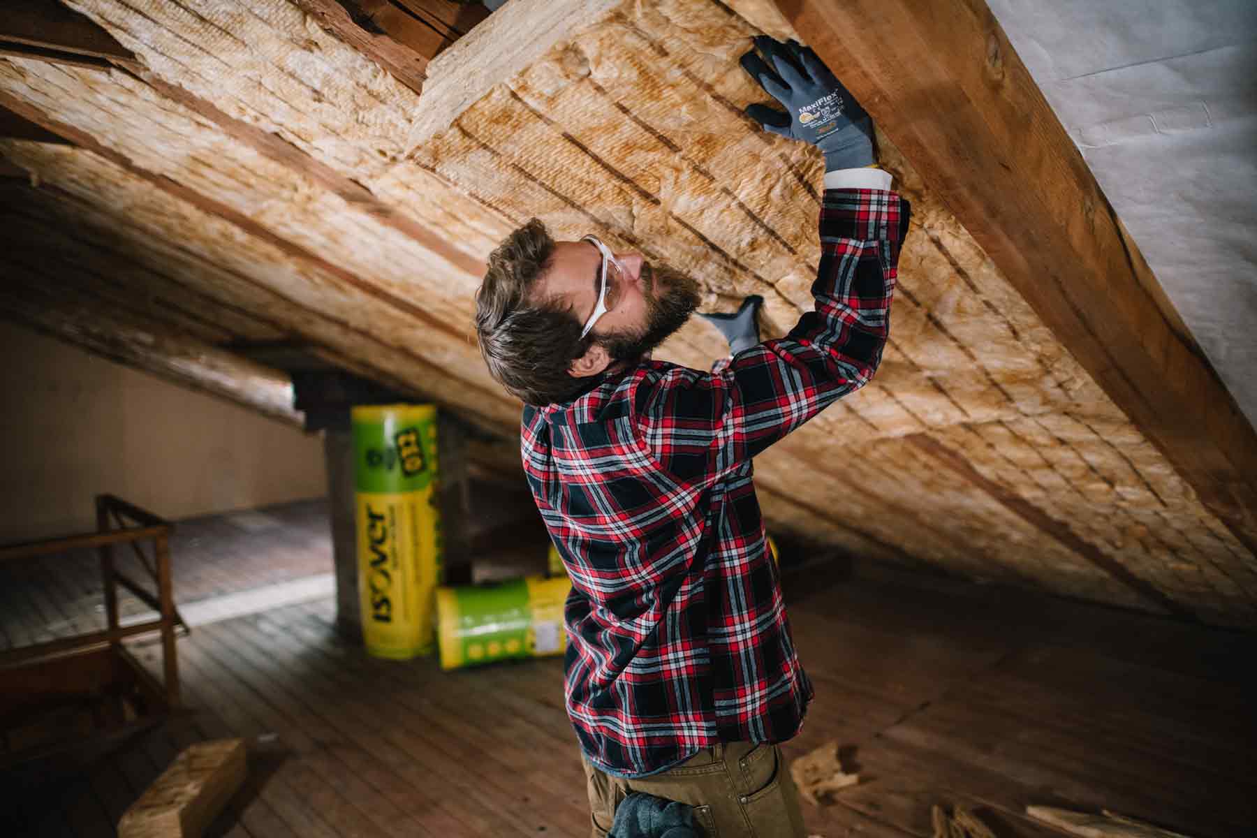Mann dämmt Dachboden mit Mineralwolle