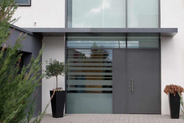 Eingangsbereich eines Hauses mit Tür, Fenster und Pflanzen