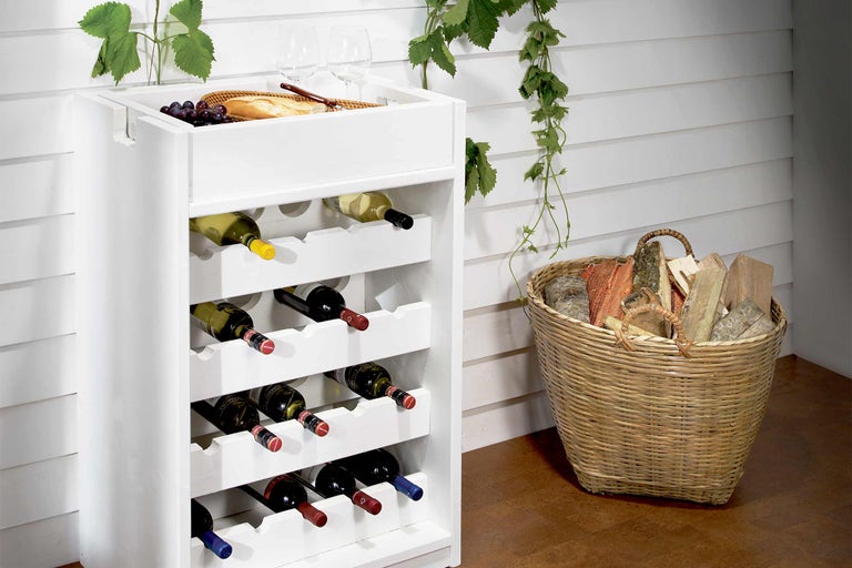 Weinregal aus Holz mit gefüllten Weinflaschen, Brot, Trauben und Holzkorb