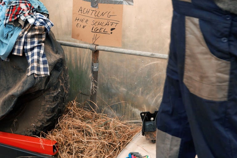 Szene mit Altreifen, Kleidung, Heu und einem Schild mit der Aufschrift: Achtung, hier schläft ein Igel