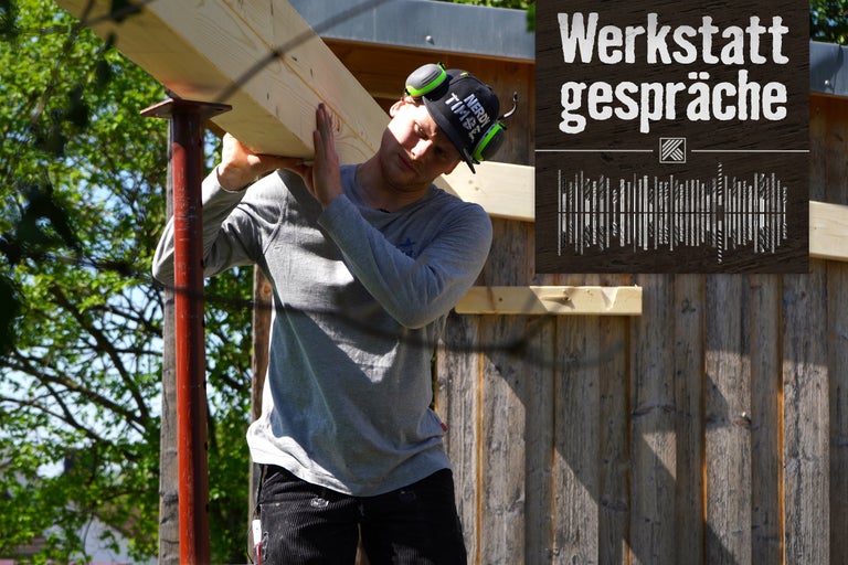 Mann trägt Holzbrett beim Bau eines Holzhauses