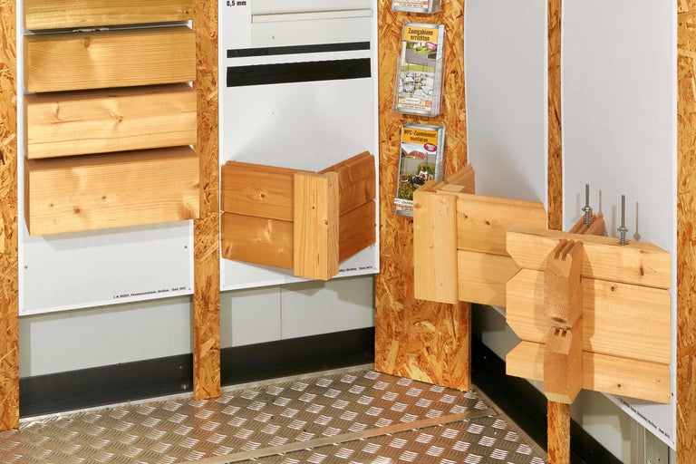 Holzkonstruktionen und Broschüren mit Informationen zu Zaungabionen und WPC-Zaunelementen.