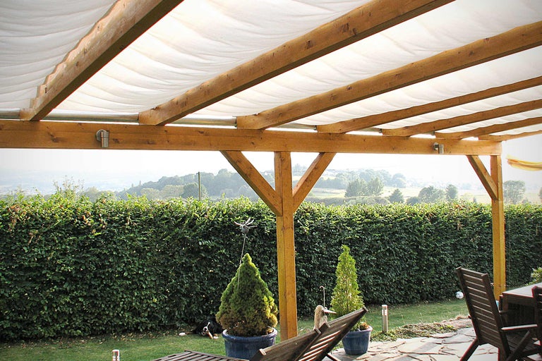Überdachte Holzterrasse mit Sonnensegel und Gartenblick