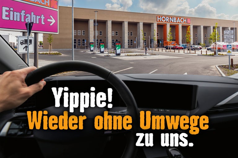 Ansicht aus dem Auto auf den Hornbach Baumarkt mit Hinweisschild zur Einfahrt.