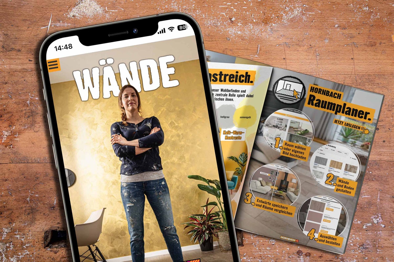 Smartphone mit Hornbach App zur Wandgestaltung und Broschüren zum Hornbach Raumplaner auf einem organisierten Holztisch.
