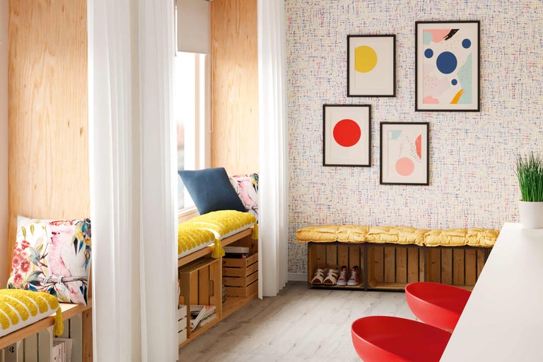 Helle Sitzecke mit Holzverkleidung, Vorhängen, Kissen und Wanddekorationen für ein gemütliches Ambiente.