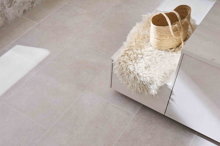 Beige Bodenfliesen in einem Raum mit Bank, Schaffell und Korb