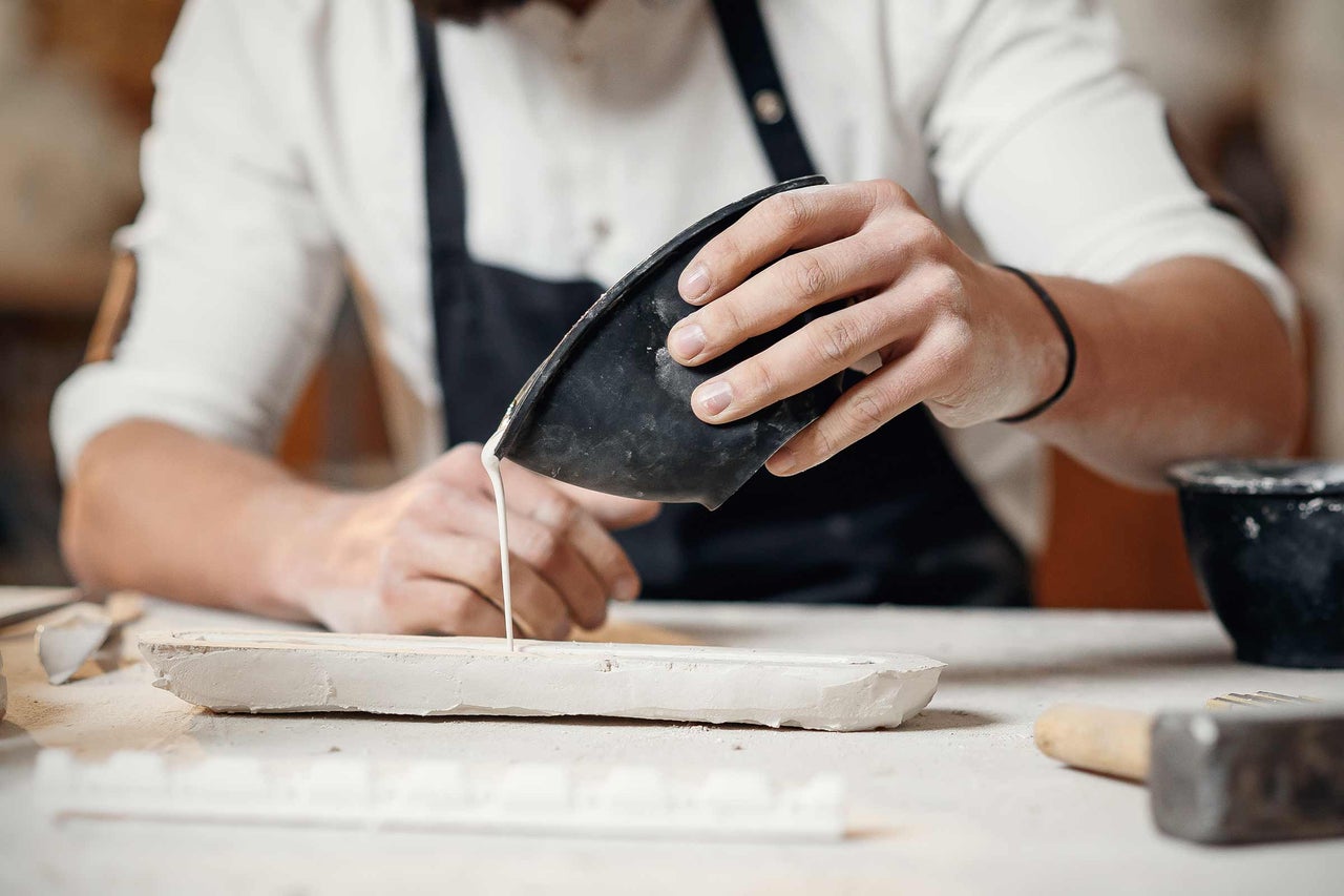 Handwerker gießt Gips in eine Gipsform.