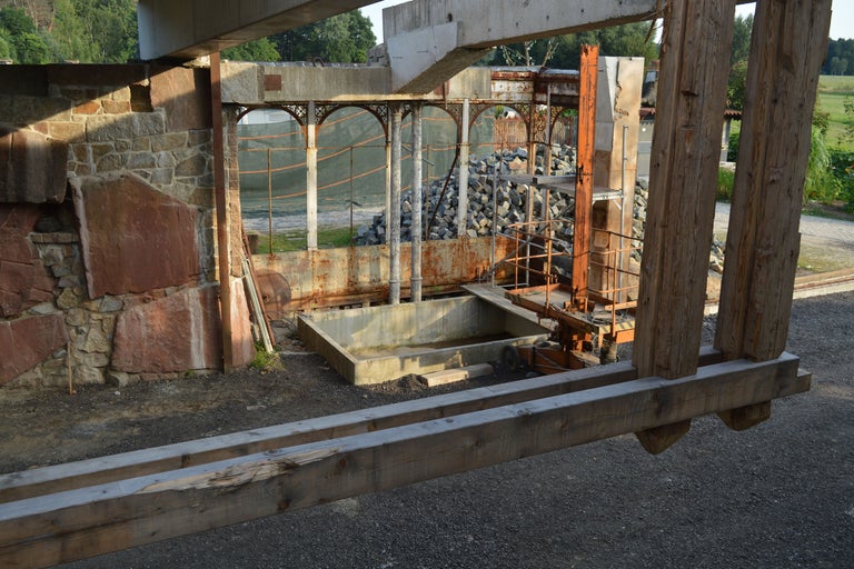 Ansicht einer Baustelle mit Steinmauer, Betonkonstruktionen und Holzträgern.