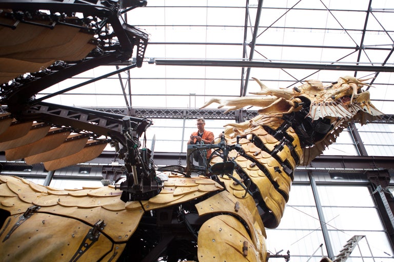 Mechanischer Drache mit Arbeiter bei Wartungsarbeiten.