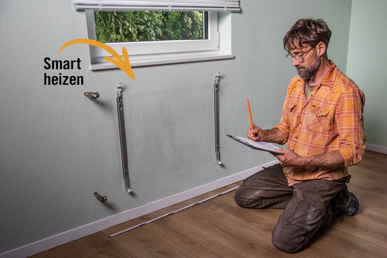 Installation von Heizkörperhalterungen an einer Wand durch einen Mann.