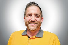 Porträt eines Mannes mit Bart und kurzem Haar, der ein Poloshirt trägt