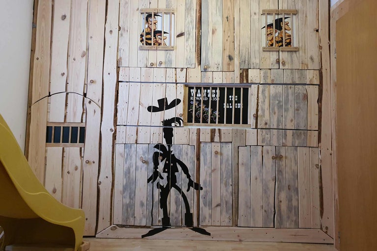 Kinderspielhaus im Wildwest-Stil mit Holzverkleidung, Gefängnis-Motiv und Rutsche