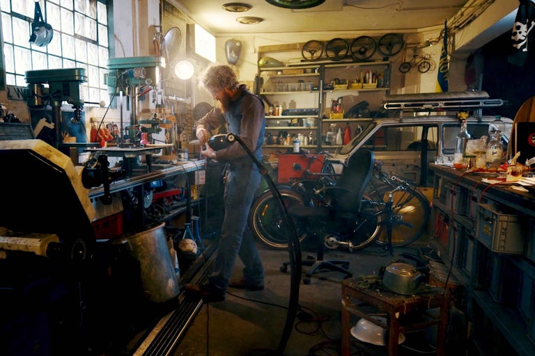 Werkstatt mit Werkbank, Werkzeugen und einer Person bei der Arbeit