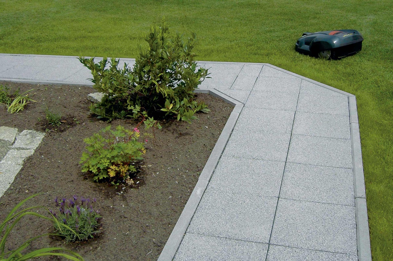 Gartenweg mit Rasenmähroboter im Hintergrund