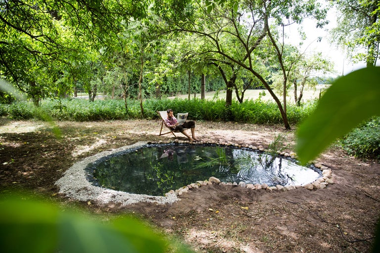 Gartenteich mit Ufergestaltung und entspanntem Mann im Liegestuhl