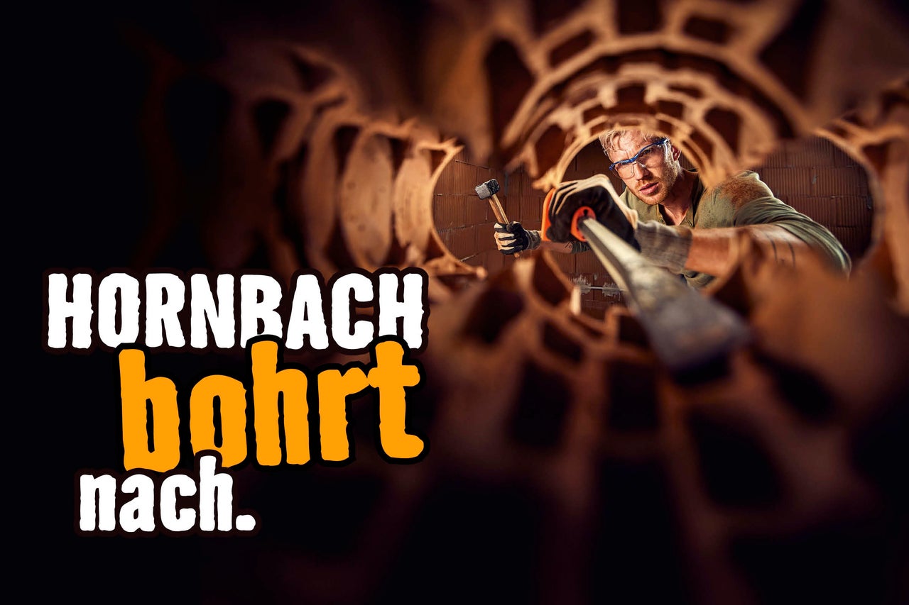 Ein Mann mit Schutzbrille und Handschuhen arbeitet mit Hammer und Meißel an einem Ziegelbauwerk. Hornbach bohrt nach.